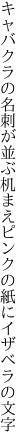 キャバクラの名刺が並ぶ机まえ ピンクの紙にイザベラの文字